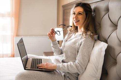 a woman sitting on a couch with a laptop at Business Hotel Plovdiv - Central Location in Plovdiv