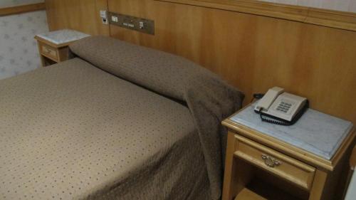 a bed in a room with a phone on a table at Gran Hotel Libertad in Buenos Aires