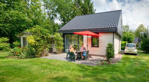 two people sitting at a table under a red umbrella at Vakantiepark Bosmeer Friesland in Noordwolde