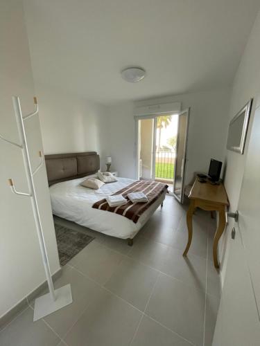 1 dormitorio con cama, mesa y ventana en Appartement CUMARU vue mer, en Saint-Florent
