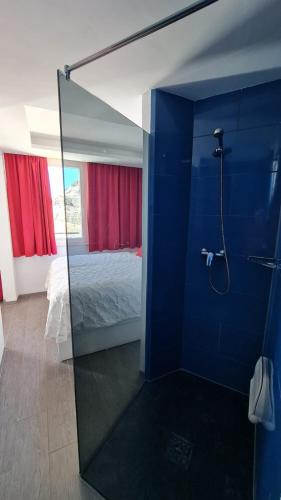 a bathroom with a glass shower with a bed at Cura Sol in Playa del Cura
