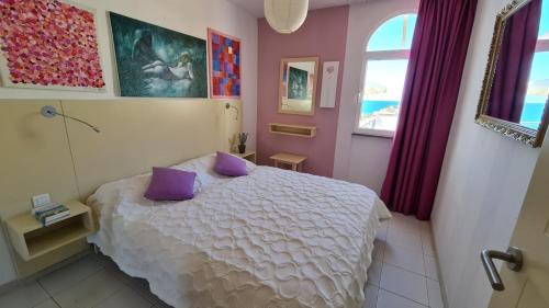 a bedroom with a white bed with purple pillows at Cura Sol in Playa del Cura