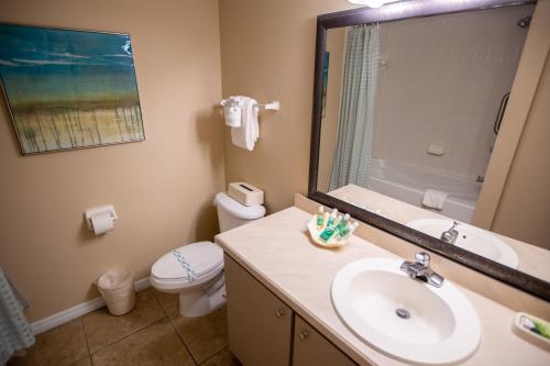 a bathroom with a sink and a toilet and a mirror at Sea Shells Beach Club in Daytona Beach
