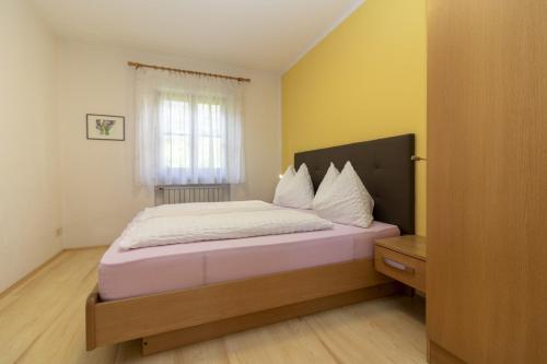 a bedroom with a bed with white sheets and a window at Stompferhof Familienapartment in Caldaro