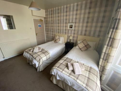 a bedroom with two beds with towels on them at Queens Hotel in St Bees