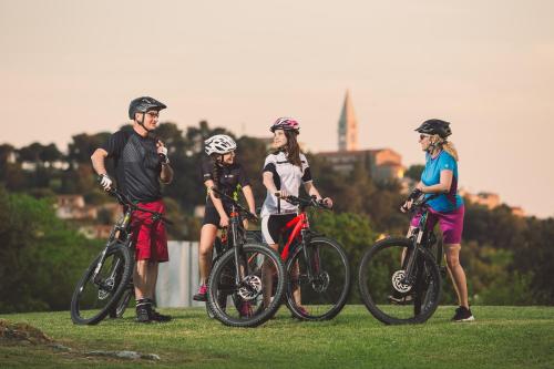 a group of people standing with bikes in the grass at Maistra Select Funtana All Inclusive Resort in Funtana