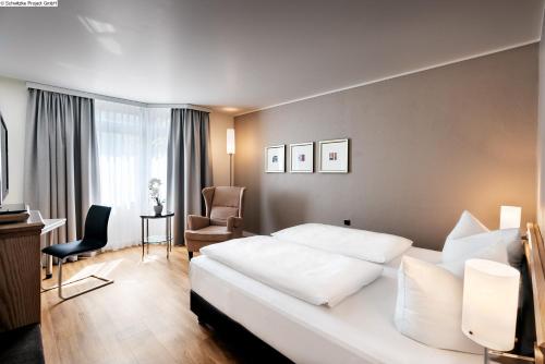 a hotel room with a bed and a chair at Mövenpick Hotel München-Airport in Hallbergmoos