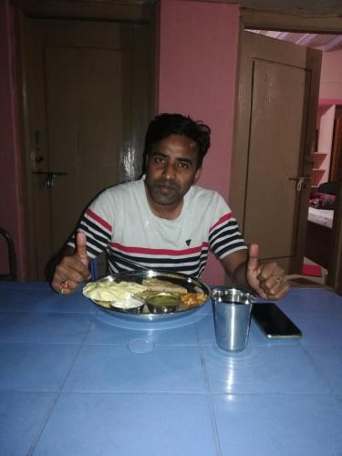 a man sitting at a table with a plate of food at Abhi Homestay Hampi in Hampi