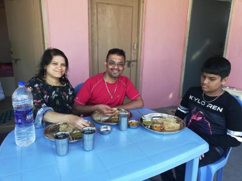 a group of people sitting at a table with food at Abhi Homestay Hampi in Hampi