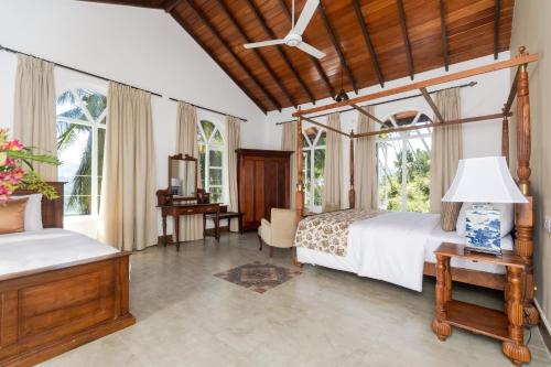 a bedroom with two beds and a desk and windows at Villa Merak, Digana in Digana