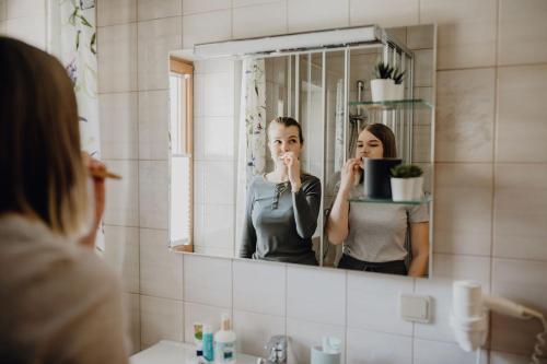 a woman brushing her teeth in front of a mirror at Dorfcafe Unken Hotelpension sWirtshaus im Dorf in Unken