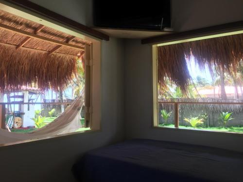 a bedroom with a window with a bed and a balcony at Parador Algaroba in Japaratinga