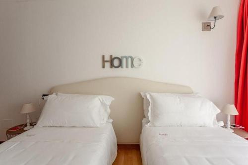 two beds in a room with a home sign on the wall at Gressoney Saint-Jean apartments by Halldis in Gressoney-Saint-Jean