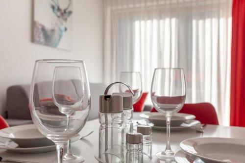 a table with three wine glasses and plates on it at Gressoney Saint-Jean apartments by Halldis in Gressoney-Saint-Jean