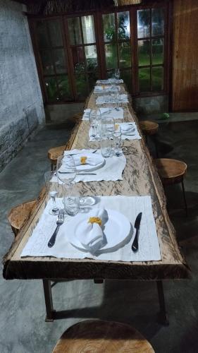 a long wooden table with plates and glasses on it at Parador Algaroba in Japaratinga