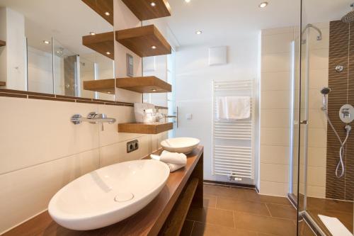 a bathroom with two sinks and a shower at Wohlfühlhotel Berwanger Hof in Obermaiselstein