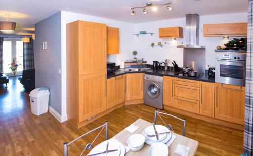 a kitchen with wooden cabinets and a table with chairs at Grand Central Friar Gate Deluxe Apartments in Derby