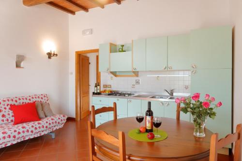 una cucina e una sala da pranzo con tavolo e bottiglia di vino di Podere I Sorbi a San Donato in Fronzano