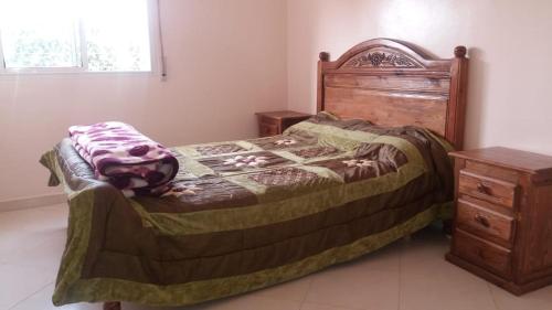 - une chambre avec un lit et une commode en bois dans l'établissement Residence Bassatine, à Temara