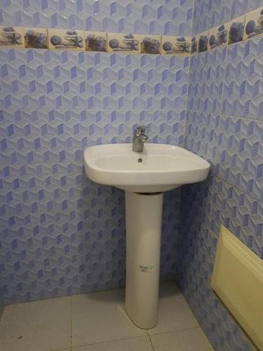 a white sink in a bathroom with blue tiles at Residence Bassatine in Temara
