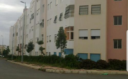 un grand bâtiment blanc sur le côté d'une rue dans l'établissement Residence Bassatine, à Temara