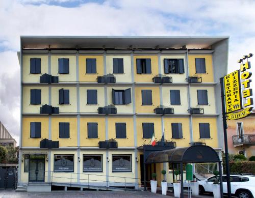 a large yellow building with a car parked in front of it at Hotel Ristorante Tre Leoni in Somma Lombardo