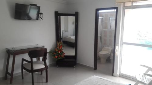 a bathroom with a mirror and a table and a chair at Hotel Miraflores RB in Ríohacha