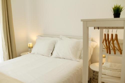 Cama blanca con almohadas blancas y mesa en Caparica Downtown Apartment en Costa da Caparica