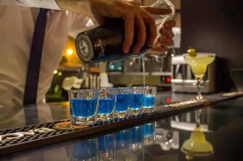 a bartender is pouring blue liquid into glasses at Fiori Hotel in Erbil