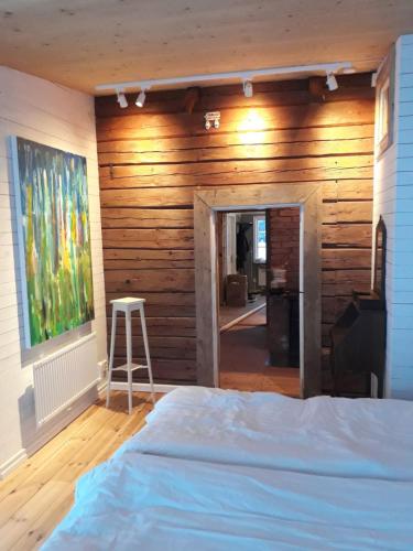 a bedroom with a bed and a wooden wall at Pilgården Fornåsa, Drängstugan in Fornåsa