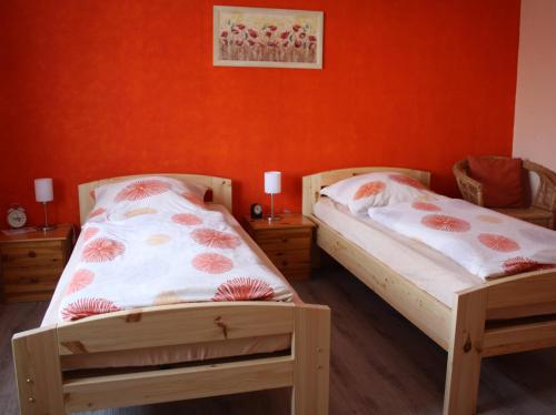 2 Betten in einem Zimmer mit orangefarbener Wand in der Unterkunft Haus Erika in Hemmoor