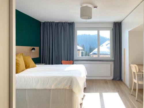 um quarto com uma cama grande e uma janela em Grüezi Laax Apartments em Laax