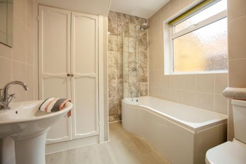 a white bathroom with a tub and a sink at Seascape in Whitley Bay