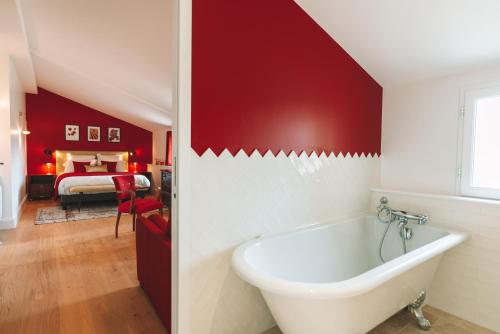 - une salle de bains rouge avec baignoire et une chambre dans l'établissement Villa Les Belles Saisons, à Saint-Émilion
