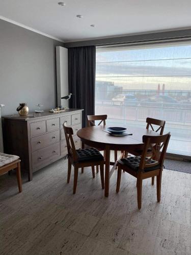 a dining room with a table and chairs and a window at Gelijkvloers zeezicht appartement Sterckx in Blankenberge