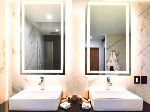 two sinks in a bathroom with two mirrors at Ramë Hotel Boutique in Guadalajara