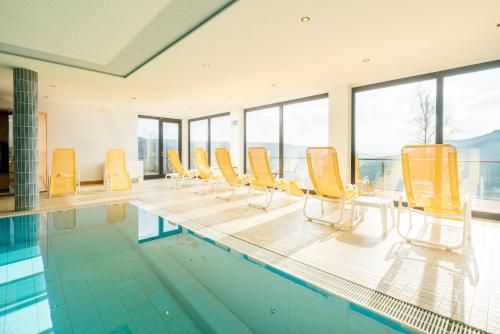 a swimming pool with yellow chairs and a row ofvationliest at Waldhotel Sonnenberg in Bollendorf