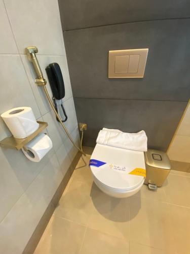 a bathroom with a toilet with a phone on the wall at Velar Inn Hotel in Taif