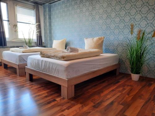 two beds in a room with wooden floors at Easy Stay Rooms in Stuttgart