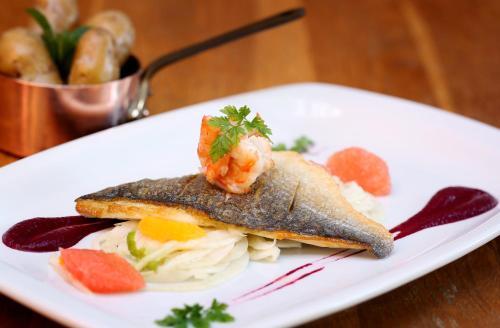 a white plate with a fish dish with shrimp on it at The Museum Inn in Farnham