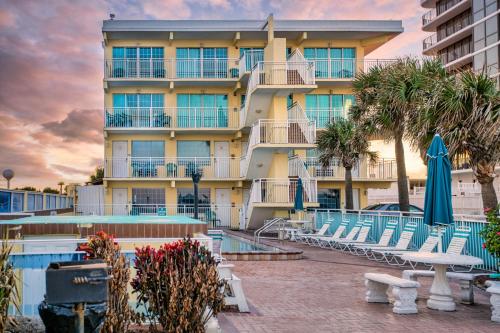 a hotel with chairs and a pool and a building at Sea Shells Beach Club in Daytona Beach