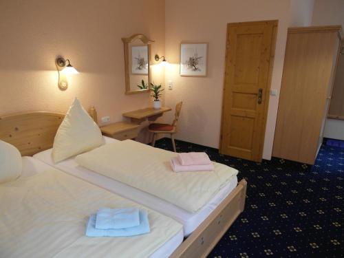 a hotel room with two beds and a desk at Pension und Gaststätte "Zur Brauschänke" in Schöneck