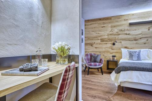 a bedroom with a bed and a desk with flowers at Hotel Sant'Orso - Mountain Lodge & Spa in Cogne