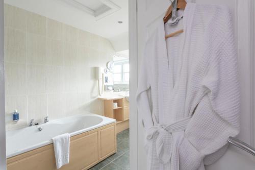 a bathroom with a bath tub and a white robe at The Lovat, Loch Ness in Fort Augustus