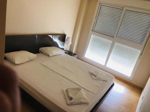 1 dormitorio con 1 cama con 2 almohadas y ventana en Punta Cormoran en La Manga del Mar Menor
