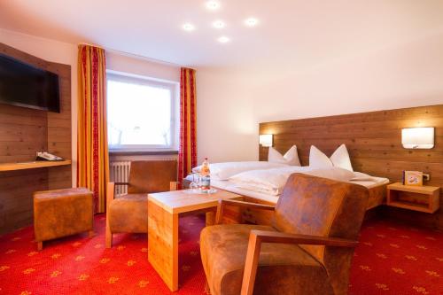 a hotel room with a bed and a table and chairs at Wohlfühlhotel Berwanger Hof in Obermaiselstein