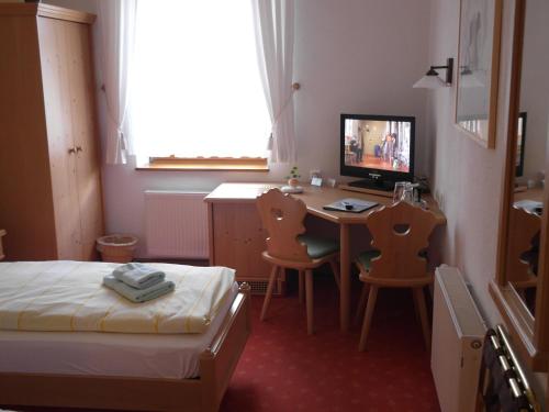 a bedroom with a bed and a desk with a computer at Pension und Gaststätte "Zur Brauschänke" in Schöneck