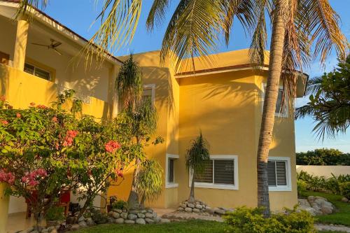 a yellow house with palm trees in front of it at Condominios JAROJE in Santa Cruz Huatulco