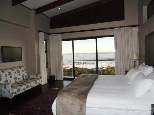 a bedroom with a bed and a view of the ocean at Whalesong Villa in Hermanus