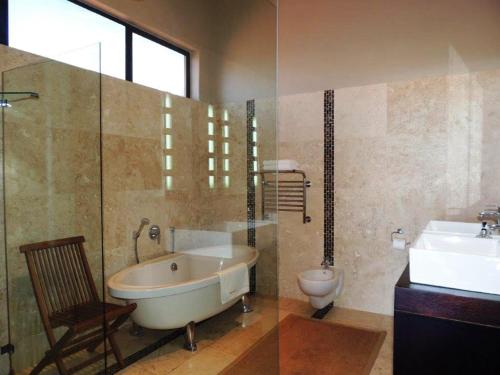 a bathroom with a tub and a toilet and a sink at Whalesong Villa in Hermanus